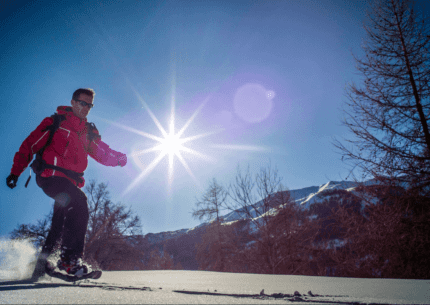 Randonneur équipé de raquettes marchant sur la neige sous un ciel bleu éclatant dans le Verdon.