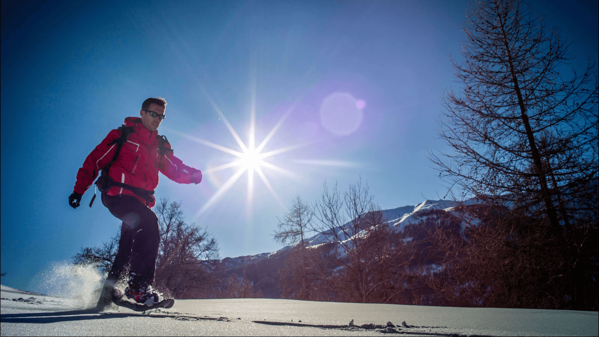 Randonneur équipé de raquettes marchant sur la neige sous un ciel bleu éclatant dans le Verdon.